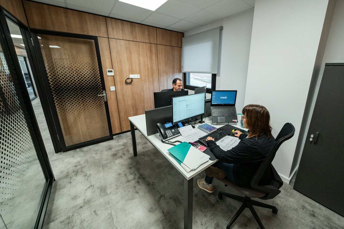 Dos profesionales trabajan en computadoras en una oficina moderna.