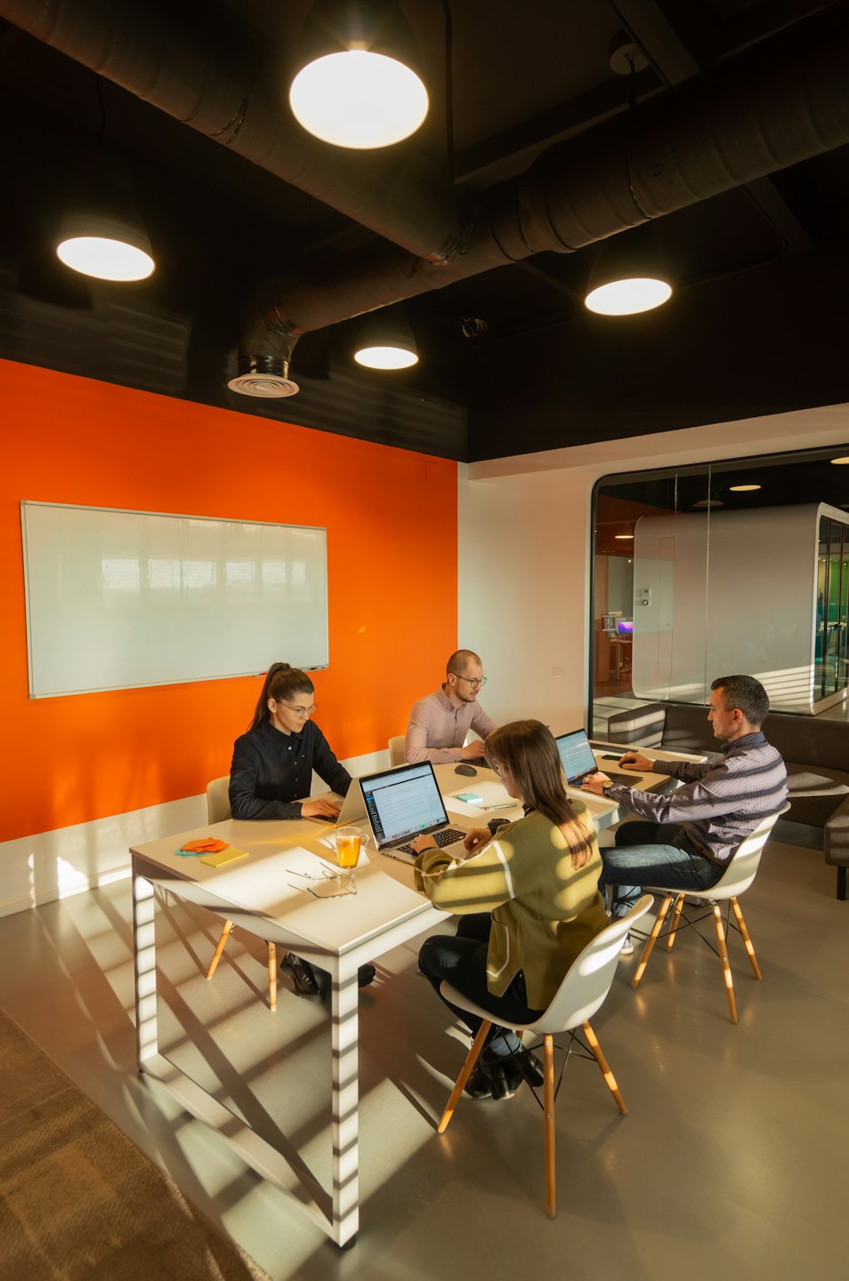 Profesionales colaboran en portátiles en una mesa de oficina moderna.